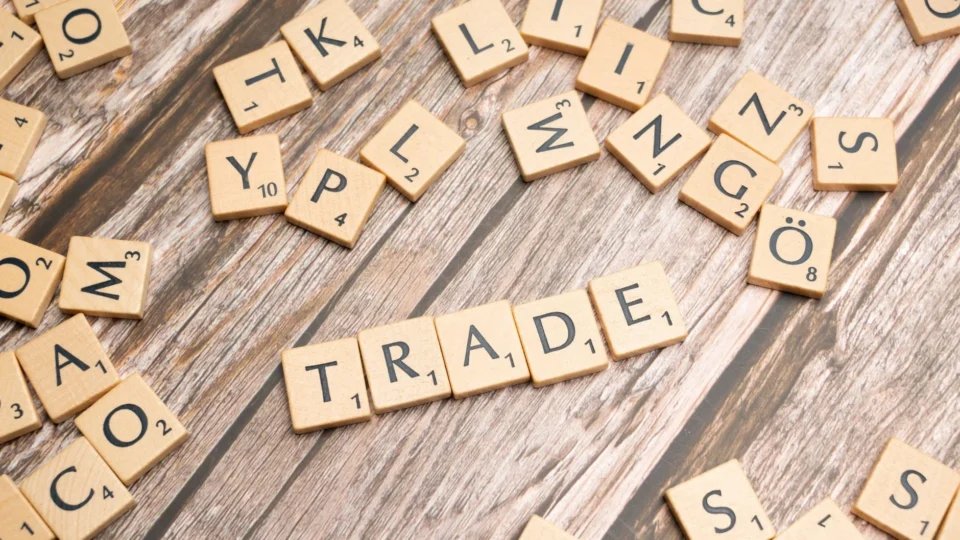 Scrabble letter tiles spelling 'trade' on a wooden surface, illustrating business concepts.