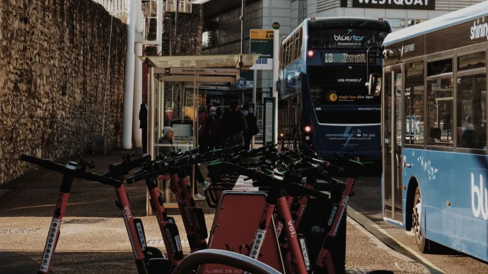 Bustling bus stop with electric scooters and buses near Westquay, England.