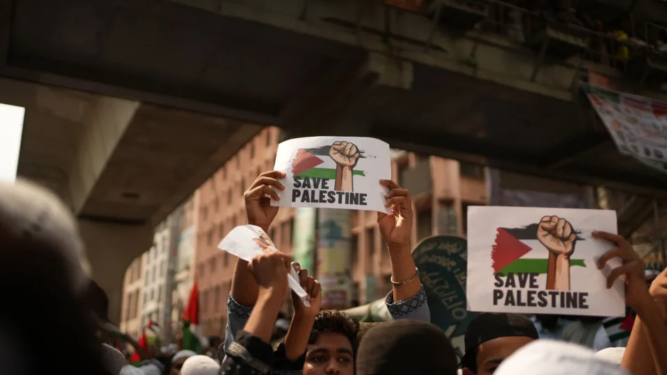 Crowd holding 'Save Palestine' signs at a protest in Dhaka, Bangladesh.