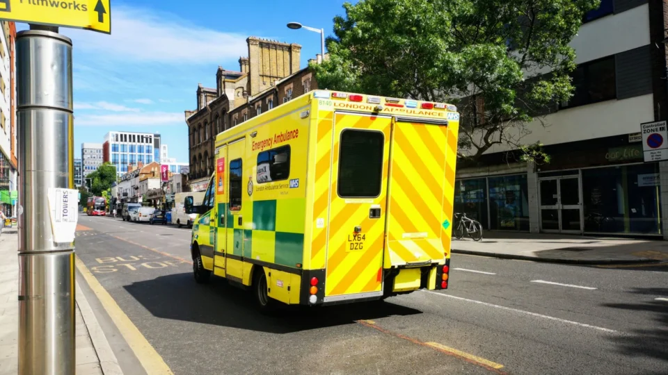 A London emergency ambulance driving through a city street in England, showcasing public health service.
