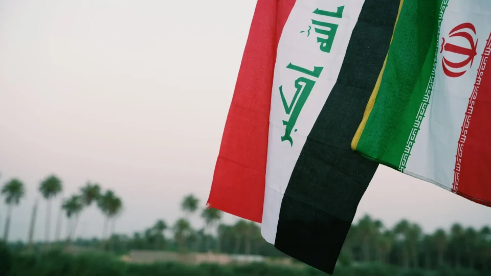 Iraqi and Iranian flags waving with palm trees in the background, Karbala, Iraq.