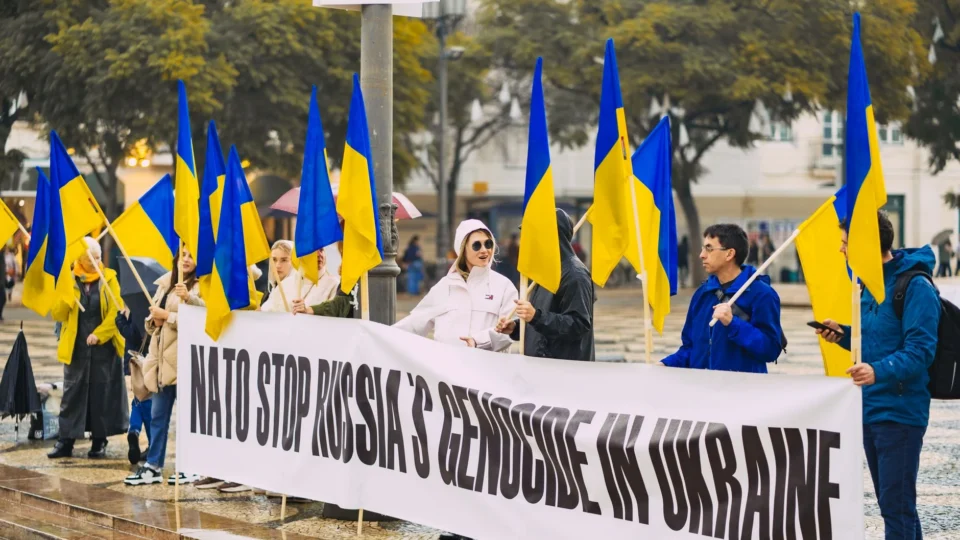 Group of people protesting against Russian actions in Ukraine with Ukrainian flags in Portugal.