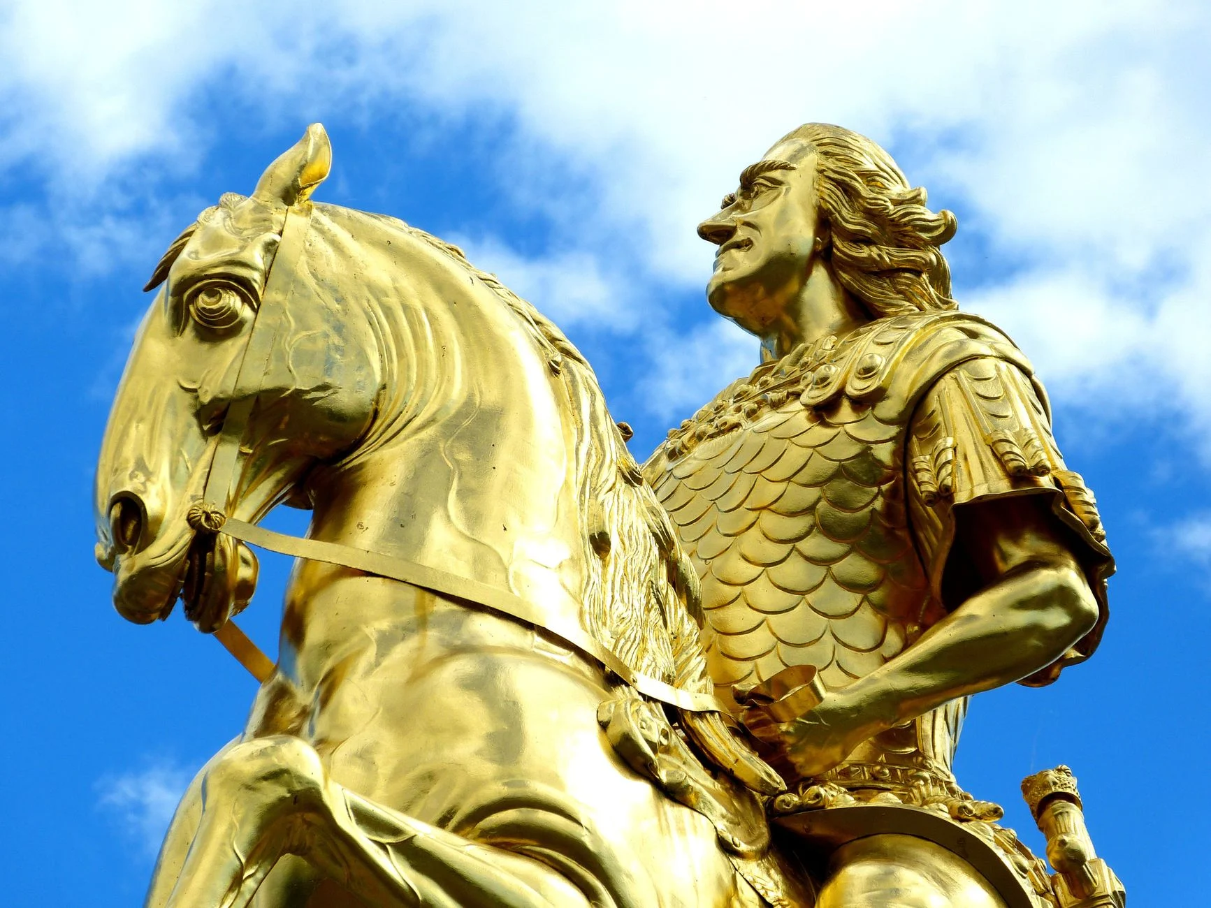 Close-up of the Golden Rider statue in Dresden with vibrant blue sky.