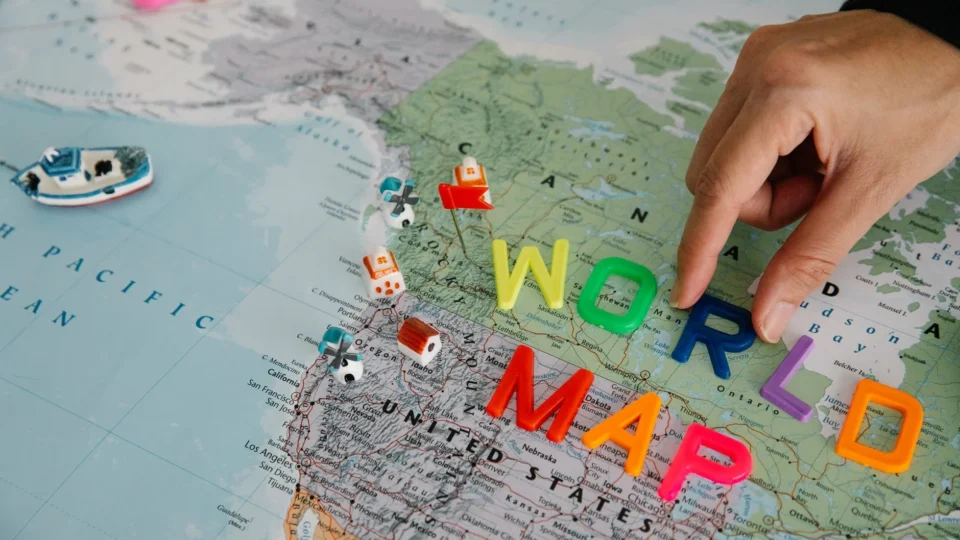 Close-up of a hand placing colorful letters on a world map, highlighting the USA.