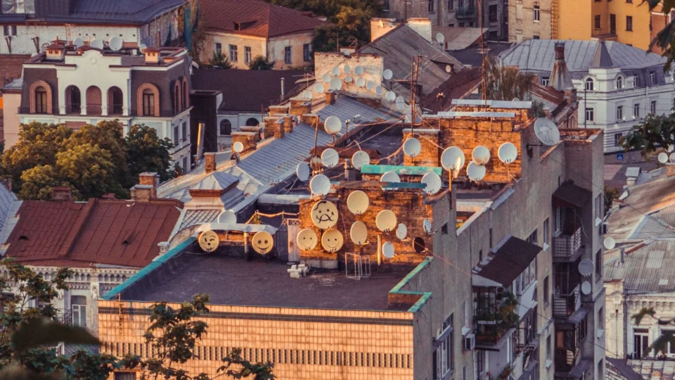 Aerial view of numerous satellite dishes on a rooftop in Kyiv, Ukraine during sunset.