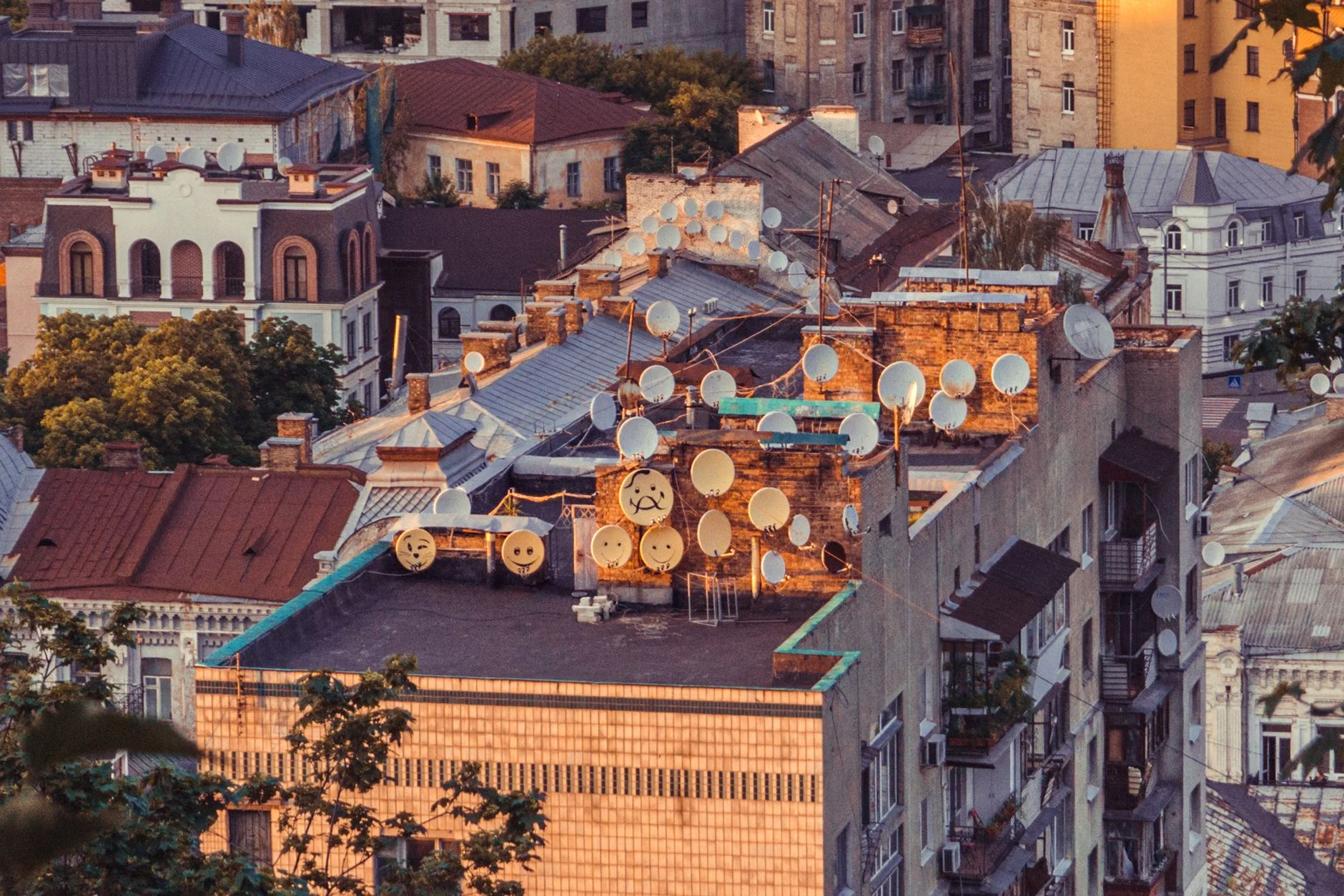 Aerial view of numerous satellite dishes on a rooftop in Kyiv, Ukraine during sunset.