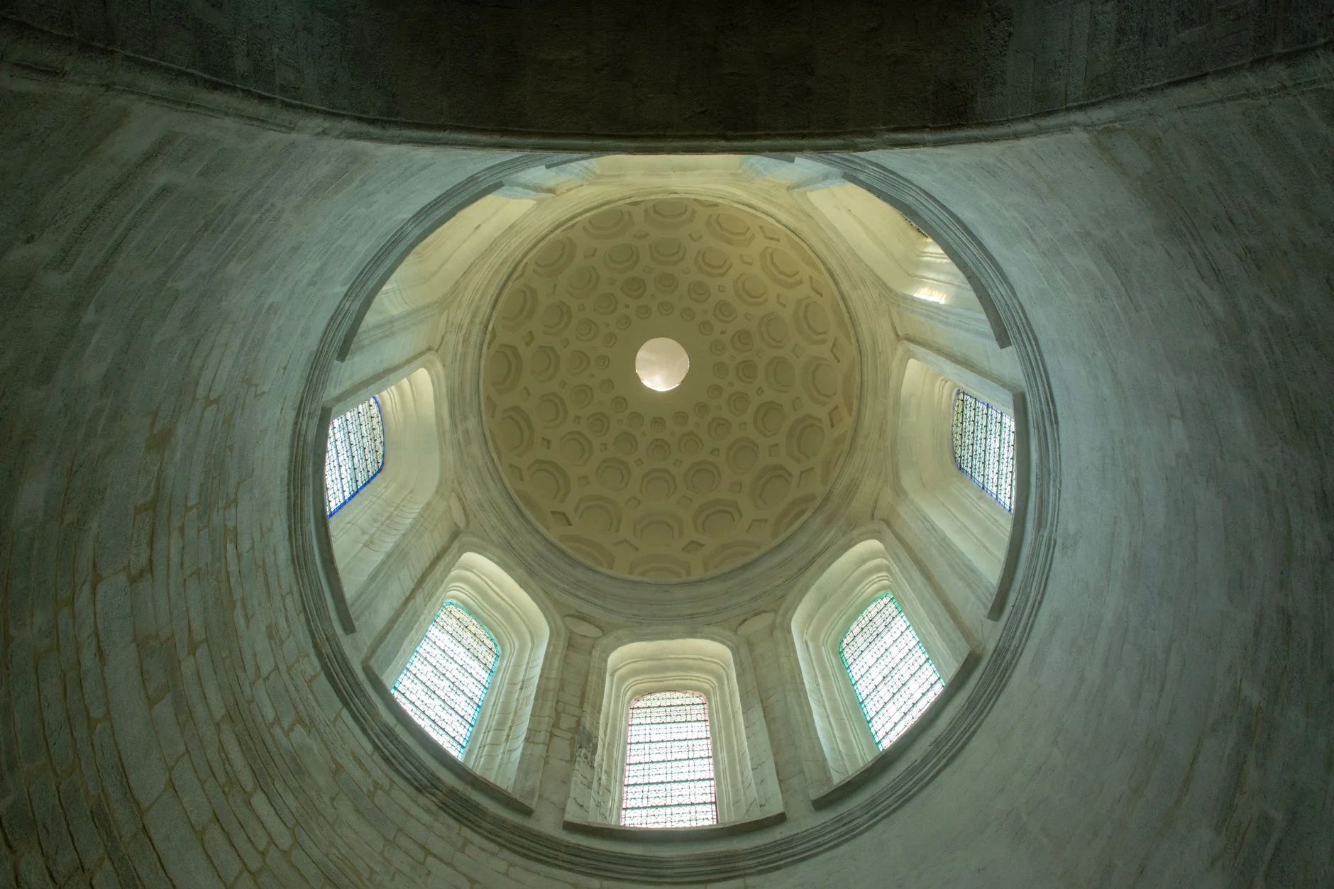 An interior view of the Saint Pierre Cathedral dome with stained glass windows.