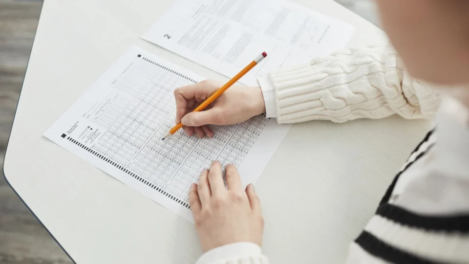 Close-up of a student filling out a multiple-choice exam in a quiet classroom setting.