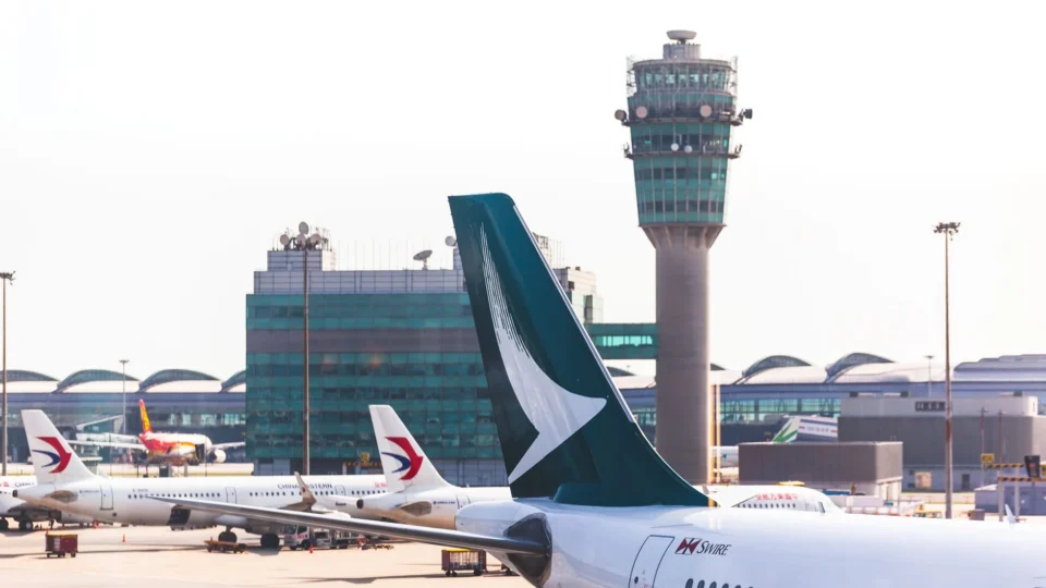 Airplane tailfin and control tower in view at a busy airport terminal.