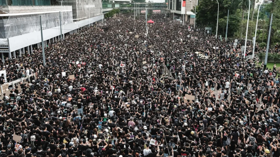 Aerial view of a large crowd gathered for a peaceful protest in Hong Kong's urban environment.