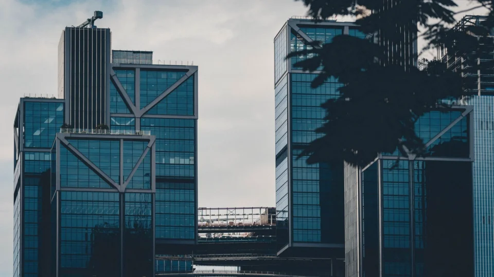 Contemporary high-rise buildings with glass facades against a cloudy sky, showcasing modern architecture.