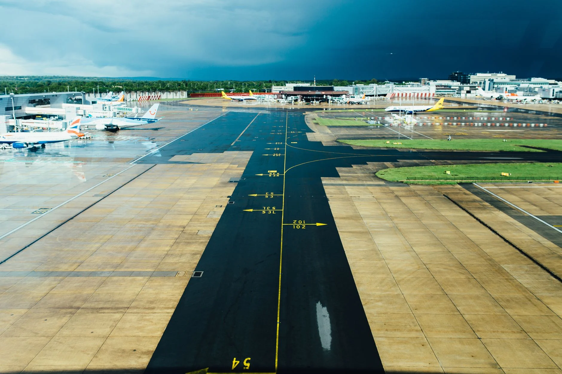 Aerial view of an airport runway with several parked planes on a cloudy day. Ideal for travel and aviation themes.