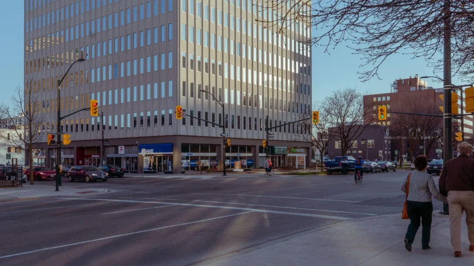Busy street scene at an urban intersection in downtown London, Canada with pedestrians and cars.
