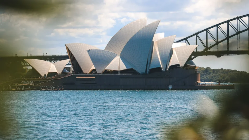Iconic view of the Sydney Opera House and Sydney Harbor Bridge on a sunny day.