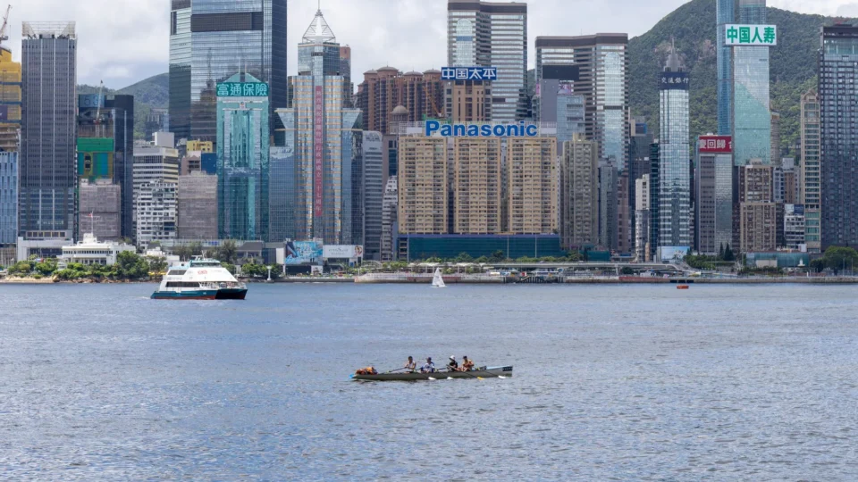 A vibrant view of Hong Kong's skyline featuring modern skyscrapers and boats on the waterfront.