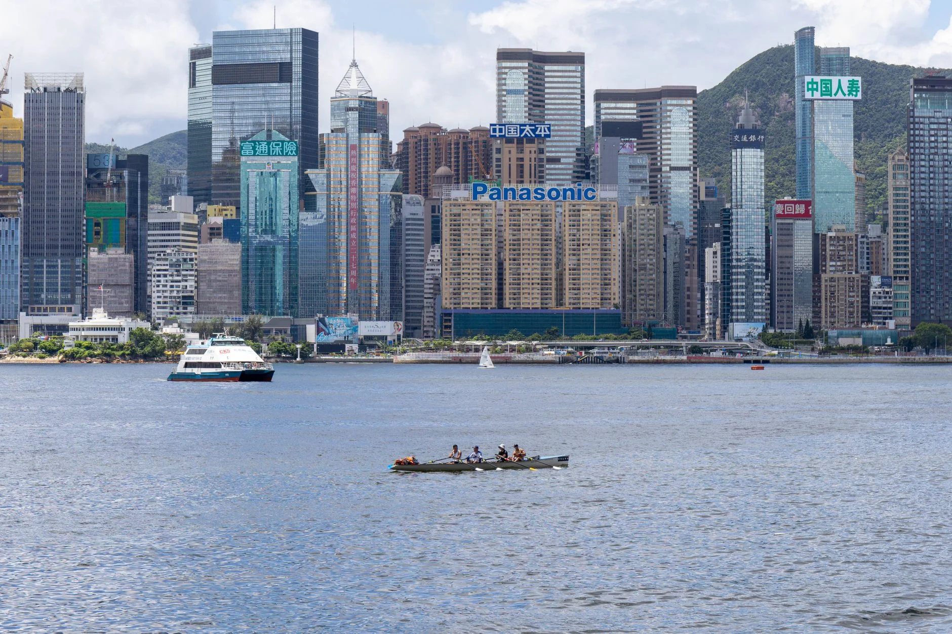 A vibrant view of Hong Kong's skyline featuring modern skyscrapers and boats on the waterfront.