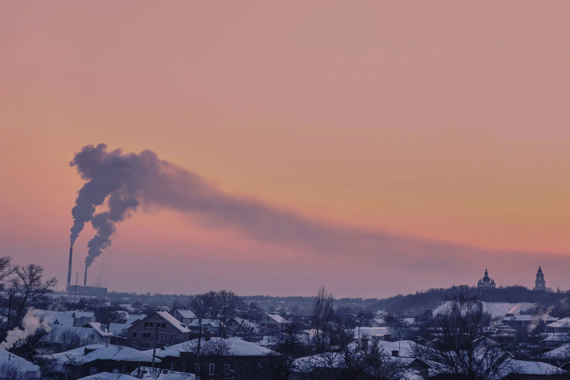 Aerial view of Chernihiv, Ukraine, with chimneys emitting smoke at sunset in winter.