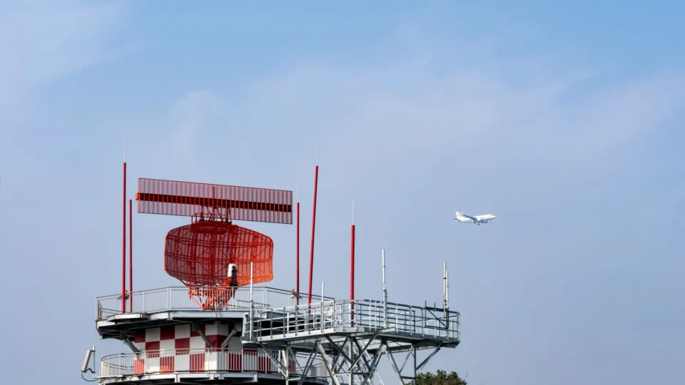 Radar tower and airplane in a blue sky, showcasing aviation technology