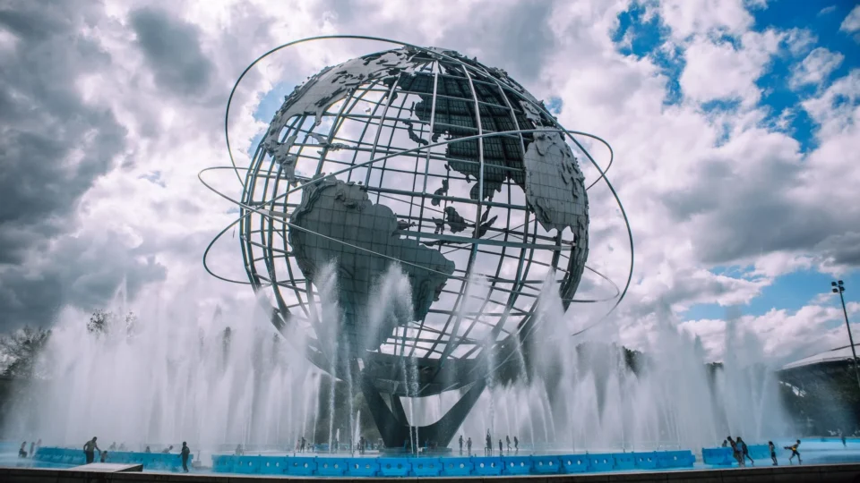 The iconic Unisphere monument in Flushing Meadows, New York, framed by a dynamic fountain display.