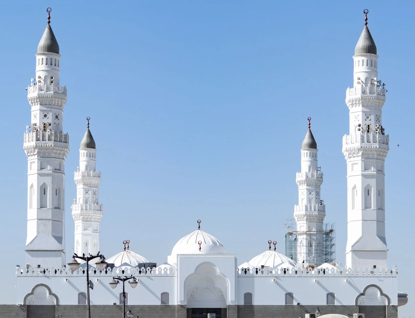 Bright daytime view of the historic Quba Mosque with its iconic minarets in Madinah, Saudi Arabia.
