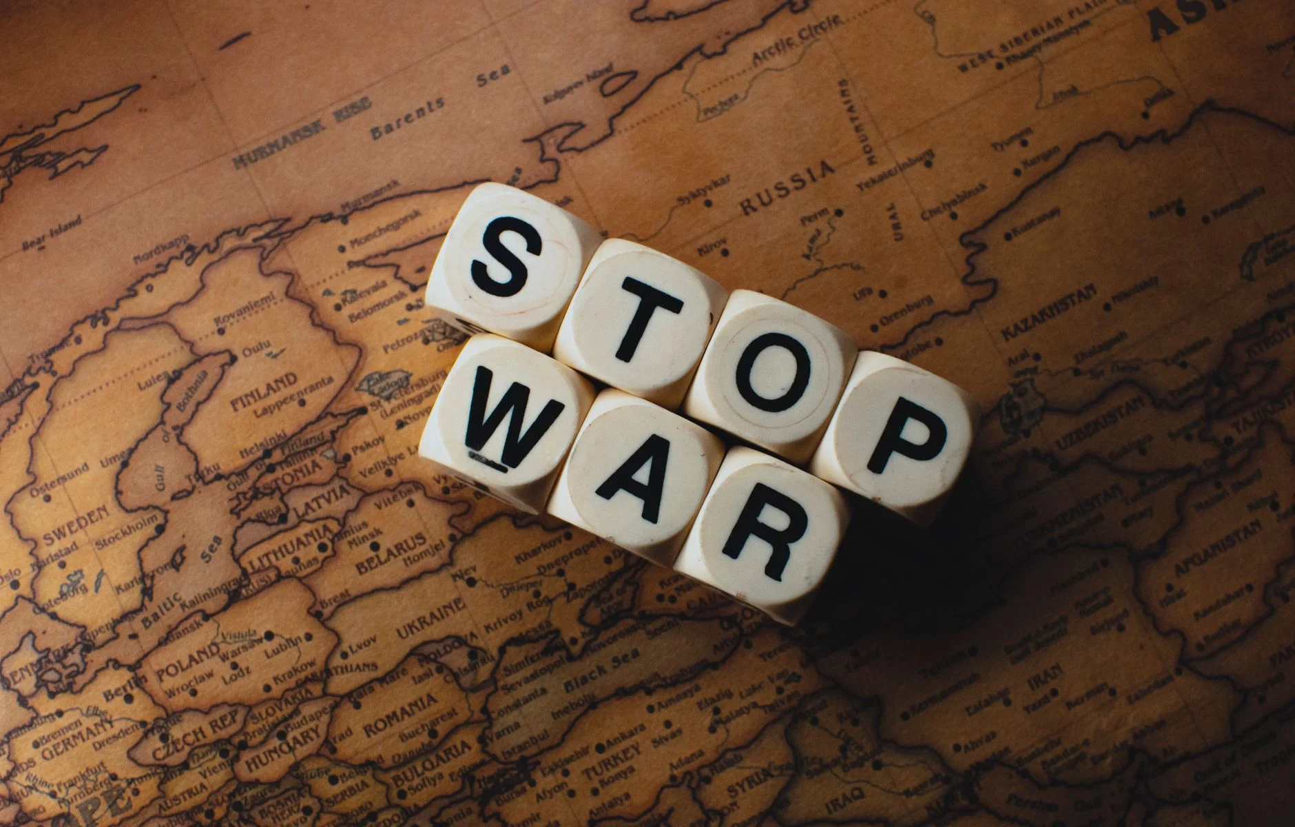 Dice with 'STOP WAR' on a vintage world map signifies peace.