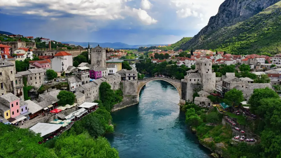 Captivating aerial shot of Stari Most bridge in Mostar, Bosnia, framed by historic architecture and lush greenery.