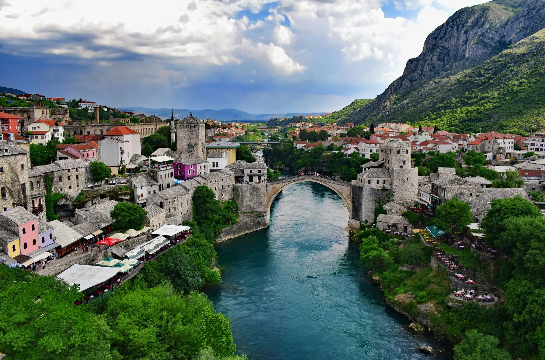 Captivating aerial shot of Stari Most bridge in Mostar, Bosnia, framed by historic architecture and lush greenery.