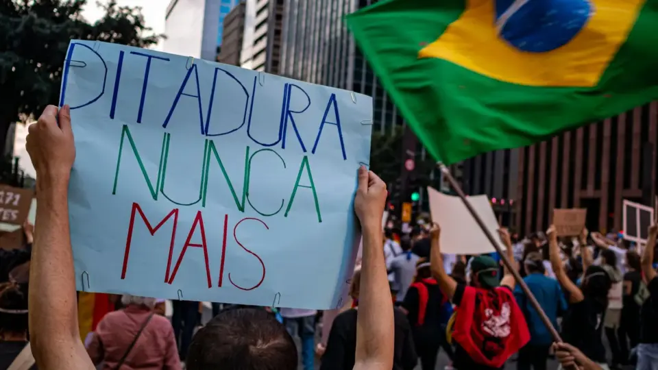 Protesters rally in São Paulo, Brazil, holding signs for human rights and democracy.