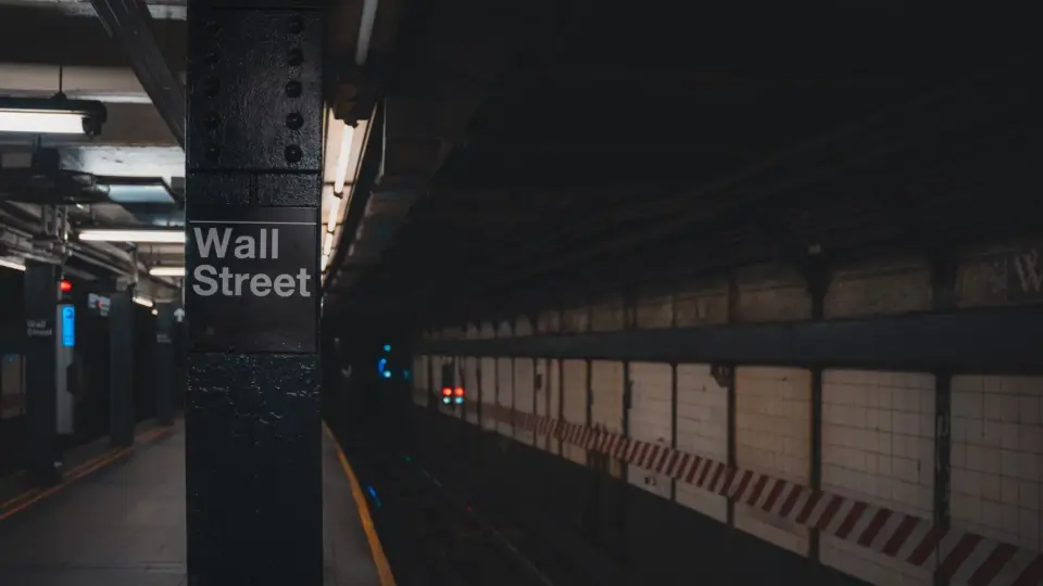 Moody view of Wall Street subway station in New York City, showcasing urban architecture.