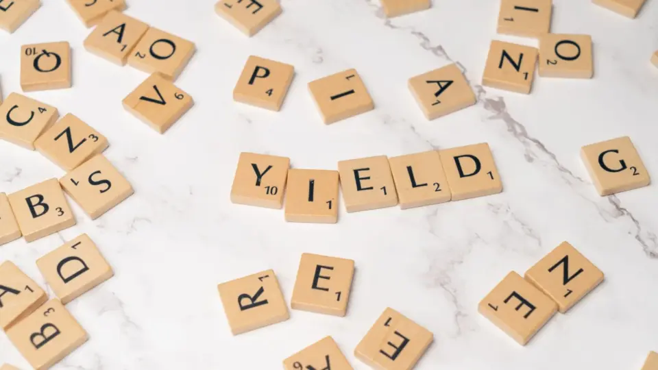 Scrabble tiles forming the word 'YIELD' on a marble surface, symbolizing finance and investment.