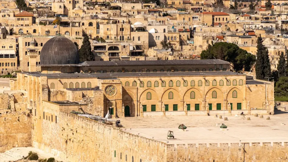 Scenic view of the Al-Aqsa Mosque amidst the historic architecture of Jerusalem's Old City, bathed in warm daylight.