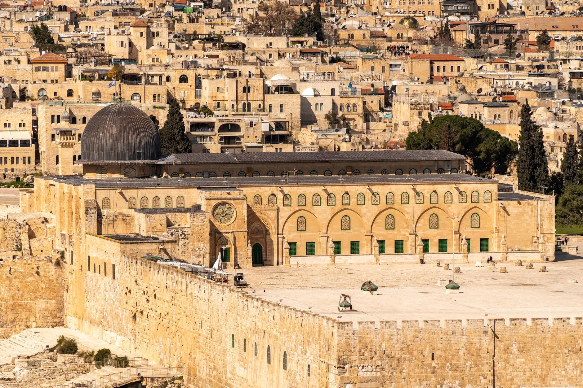 Scenic view of the Al-Aqsa Mosque amidst the historic architecture of Jerusalem's Old City, bathed in warm daylight.