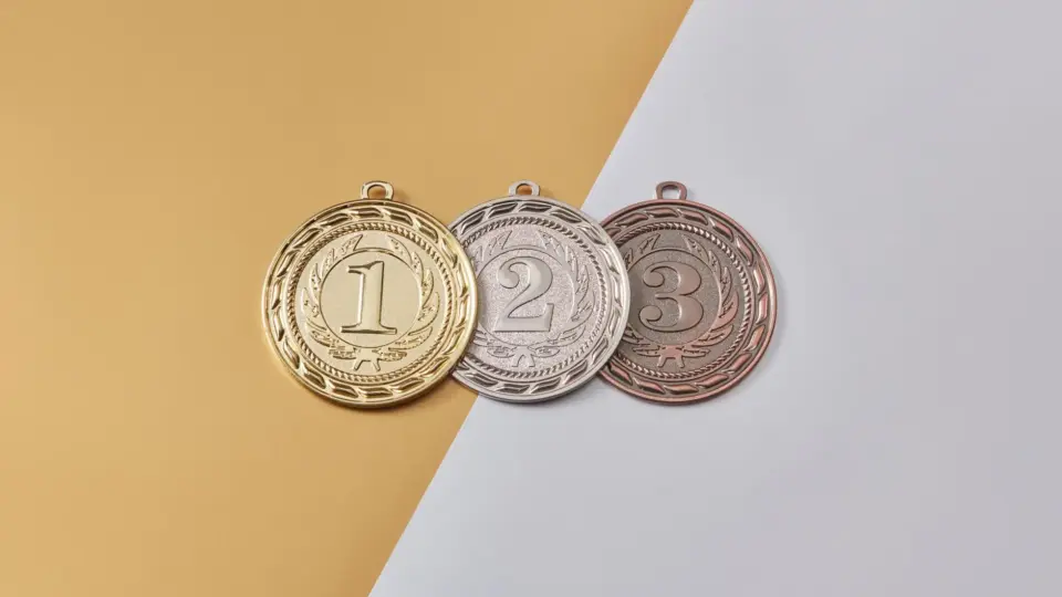 Gold, silver, and bronze medals placed on a modern split-color background, symbolizing achievement.