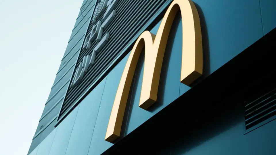 Large fast food restaurant golden arch sign on a modern building facade.