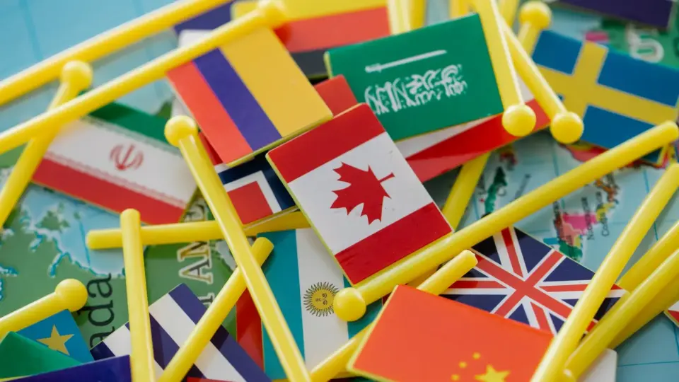 Colorful mini flags of countries on a world map, symbolizing global connections.