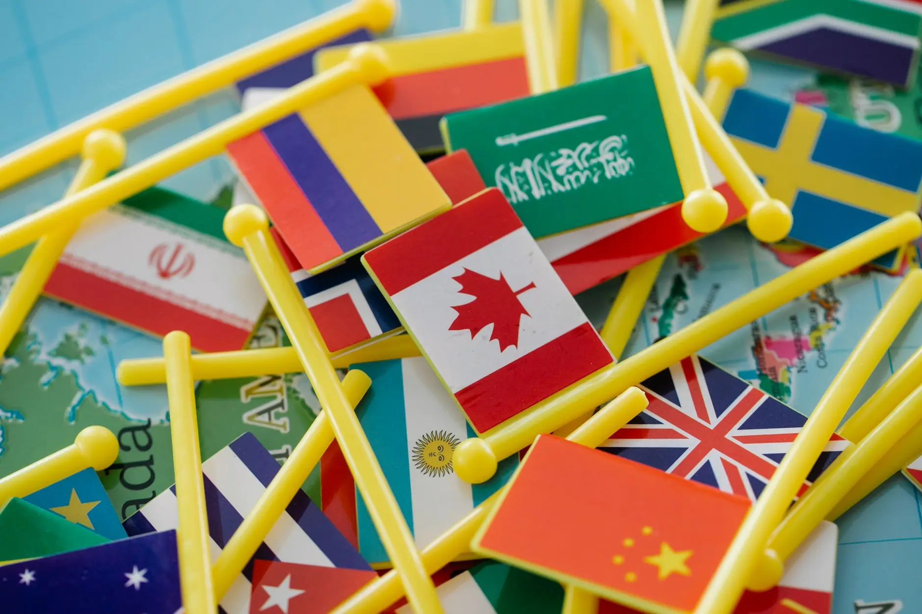 Colorful mini flags of countries on a world map, symbolizing global connections.
